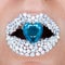 Beautiful closeup with female lips with white brilliants and blue brilliant in mouth. Make-up, glitter sparkles on lip
