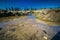 Beautiful closeup of a river surrounded by mossy rocks against wooden cuts at daytime