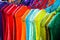 Beautiful closeup shot of colorful lace clothes on blue hangers in a row at a market