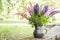 Beautiful closeup of unique vase of black pottery with lupines blossoms in summer morning sunlight