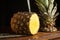 Beautiful closeupshot of a pineapple with its cut crown on a wooden board with sharp vintage knifes