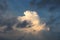 A beautiful cloud illuminated by sun during sunset. Blue sky and dark gray clouds around the edges. Evening sky. Climate