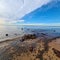 Beautiful cloudscape over a calm waveless sea with a rocky coastline