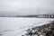 Beautiful coast of the frozen sea in winter. Bridge in the distance.