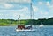 A beautiful coastline in the water in Germany, Schlei, with a tiny boat at a pier in front of beautiful blue sky and white clouds