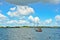 A beautiful coastline in the water in Germany, Schlei, with a tiny boat at a pier in front of beautiful blue sky and white clouds