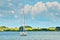 A beautiful coastline in the water in Germany, Schlei, with a tiny boat at a pier in front of beautiful blue sky and white clouds