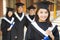 Beautiful college graduate holding diploma with classmates