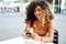 Beautiful colombian woman with afro hairstyle using mobile phone, flirting with someone