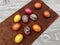 Beautiful colored Easter eggs on a brown rattle against a gray wooden table.