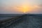 Beautiful colourful sunset over endless empty road in middle of desert. Asphalt highway in Tunisia, North Africa.