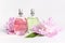 Beautiful composition with perfume and flowers. Perfume bottle, pink flowers peonies green leaves on light background Flat lay