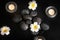 Beautiful composition with spa stones, flowers and burning candles on black background, top view