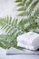 Beautiful composition of spa treatment with white cotton towels on marble plate and fern branches, minimal spa relax concept, eco
