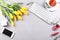 Beautiful composition with yellow tulips, gift, keyboard and mobile phone on grey background