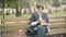 Beautiful concentrated senior woman putting on eyeglasses and opening book sitting in autumn park. Portrait of absorbed