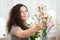Beautiful concentrated young woman florist making bouquet in shop