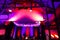 Beautiful concert hall in bright purple, violet and red light, with metal costruction and professional lighting. Defocused stage.