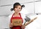 Beautiful cook woman confused and frustrated face expression wearing red apron asking for help holding rolling pin