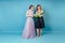 Beautiful coordinator seamstress woman and bride discuss the details of wedding dress in the studio on a blue background