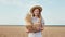 Beautiful country lady with box of a fresh bread she standing in the middle of a young wheat field looking straight to