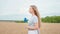 Beautiful country lady with a long curly hair walking through the wheat field and holding a colorful wind spinner in