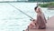 Beautiful couple fishing on lake together, man sitting with rod on dock, love couple, lovers sitting