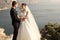 Beautiful couple. gorgeous bride in wedding dress posing with elegant groom on sea cost