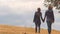 Beautiful couple holding hands, walking together on hill, autumn date outdoors