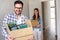 Beautiful couple just moving into new apartment holding boxes