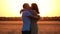 A beautiful couple in love in a wheat field at sunset. The woman runs to the man kisses and embraces him. Happy family