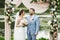 A beautiful couple of lovers near the wedding arch, decorated with fresh flowers, a young beautiful woman in the wedding