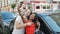 Beautiful couple make selfie by smartphone standing by car at street