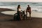 A beautiful couple on a motorbike meets the sunset by the sea. A couple in love on the beach meets the sunset.