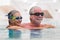 Beautiful couple of two seniors together at the swimming pool having fun - woman hugged at her husband smiling with love