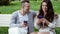 Beautiful couple uses the phone on a bench in the park, shopping online