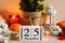 Beautiful cozy home decor composition with candles, lantern, Christmas tree, calendar dated 25 December, knitted sweater and plaid