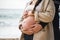 Beautiful cropped image of a bare belly of a pregnant woman embraced by her husband