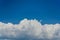 Beautiful Cumulus clouds on the background of a strip of blue sky. Lush cumulus clouds wide band in the summer blue sky
