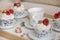 Beautiful cupcakes and coffee cup backgroud. Delicious  cupcakes with whipped cream topping and raspberries. Tea cups and cakes on