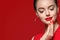 Beautiful curle hair female in red with red lips and dress manicure, beauty rose over red background