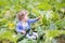 Beautiful curly baby girl next to zucchini plant