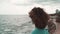 Beautiful curly brunette woman looking at the sea on a cloudy day.