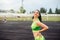 Beautiful curly girl flexing muscles in the stadium. The girl goes in for sports. Light green tracksuit