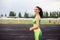 Beautiful curly girl flexing muscles in the stadium. The girl goes in for sports. Light green tracksuit