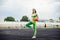 Beautiful curly girl flexing muscles in the stadium. Warm up with the ball. The girl goes in for sports. Light green tracksuit