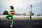 Beautiful curly girl flexing muscles in the stadium. Warm up with the ball. The girl goes in for sports. Light green tracksuit