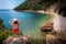 Beautiful curly girl sitting on the beach, vacation mood. Relaxed woman thinking looking away on the beach. Red bikini and hat