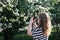 Beautiful curly girl taking picture of blooming tree