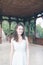 Beautiful curly hair girl in a light blue simple dress in a pavilion in a garden